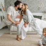 Playful morning with parents stretching and a toddler playing in the bedroom.